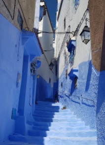 Escalinatas y bajos azules de una calle de Chefchaouen con casas encaladas en blanco